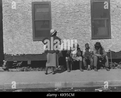 Photographie en noir et blanc d'une famille afro-américaine, une femme, deux hommes et un garçon, devant l'hôtel de ville, Belle Glade, Florida, 1939. À partir de la Bibliothèque publique de New York. Banque D'Images