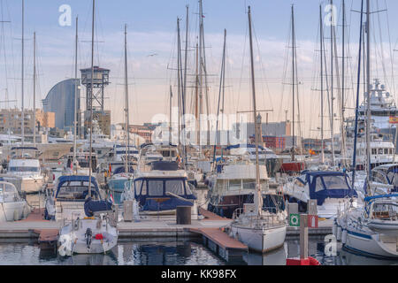 Vue sur le port de Barcelone au coucher du soleil avec des bateaux et l'Hôtel W à l'arrière-plan. Banque D'Images