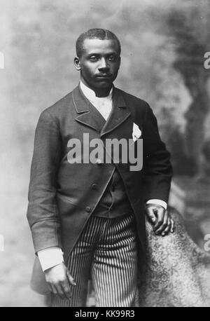 Sepia studio portrait d'un homme afro-américain, trois quarts, habillé en veste, gilet, cravate et pantalon à rayures, 1900. À partir de la Bibliothèque publique de New York. Banque D'Images