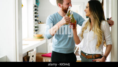 Couple heureux de boire une bière et toasting at home Banque D'Images