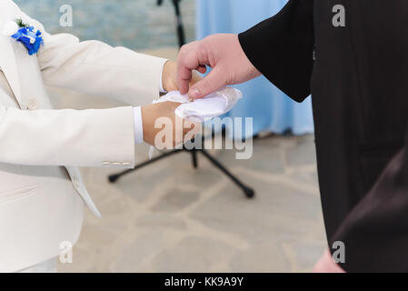 Petit garçon donne les anneaux de mariage pour le marié en costume bleu lumineux. Banque D'Images