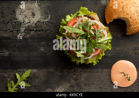 Cheeseburger sur une ancienne surface en bois de couleur sombre. hamburger avec la sauce et le ketchup sur une ancienne surface en bois de couleur sombre Banque D'Images