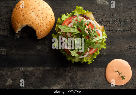 Cheeseburger sur une ancienne surface en bois de couleur sombre. hamburger avec la sauce et le ketchup sur une ancienne surface en bois de couleur sombre Banque D'Images