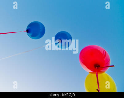 De nombreux ballons colorés lancé à partir de la les enfants heureux volant dans le ciel bleu Banque D'Images