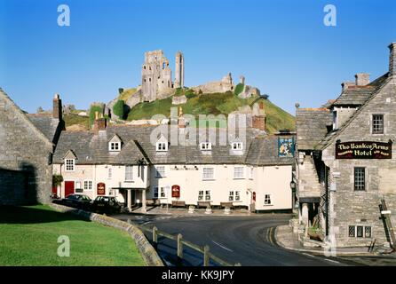 Ruines du château de Corfe s'élever au-dessus de la Greyhound pub dans l'ancien village de Corfe Castle, Dorset, Angleterre Banque D'Images