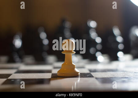 Soldat chessbord pion seul face à de nombreux ennemis la lumière unique Banque D'Images