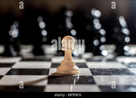 Soldat chessbord pion seul face à de nombreux ennemis la lumière unique Banque D'Images