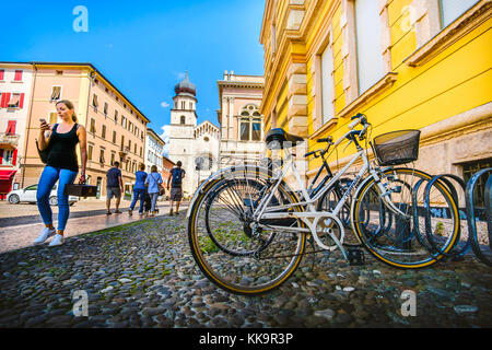 Les vélos garés près de la la cathédrale de trente, une fille à pied tout en regardant son smartphone - Trento, Italie, 14 août 2017 Banque D'Images