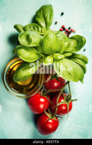 Tomates savoureuse avec des feuilles de basilic frais et les olives huile sur planche en bois rustique Banque D'Images