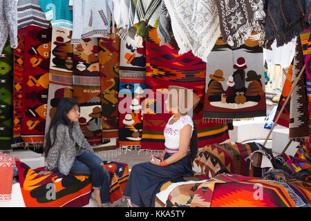 Deux jeunes femmes équatoriennes locales parler dans une échoppe de marché, marché Otavalo Otavalo, Equateur, Amérique Latine Banque D'Images
