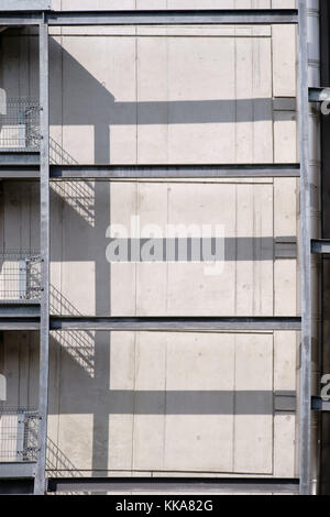 Un garde-corps en acier avec un escalier extérieur symétrique jette des ombres sur un mur de béton. Banque D'Images