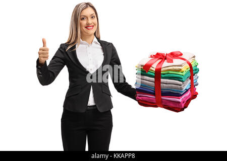 Femme vêtue de façon formelle avec une pile de paniers et des vêtements repassés enveloppés de ruban rouge comme un don Faire un pouce vers le haut signe isolé sur fond blanc Banque D'Images