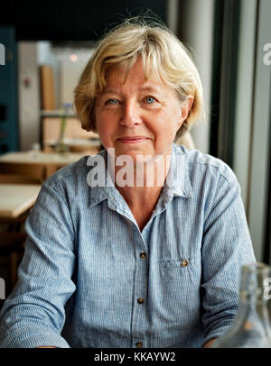 Smiling blonde woman at a restaurant. age 55-65 Banque D'Images