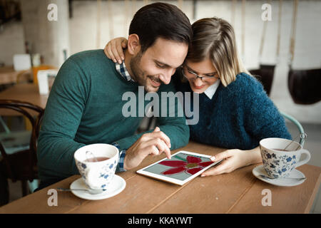 Jeune beau couple using tablet in coffee shop Banque D'Images