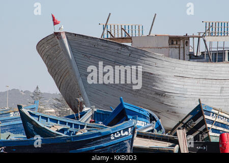 Les petits bateaux de pêche bleu s'asseoir sur le port en face de la coque d'un chalutier de pêche étant construit sur un côté Banque D'Images