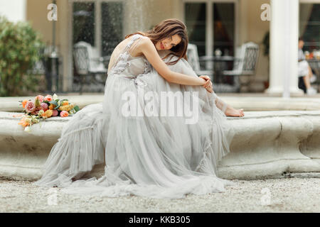 La mariée est assise près de la fontaine vintage Banque D'Images