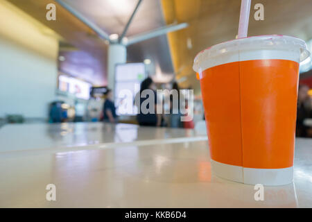 Auckland, Nouvelle-Zélande - 27 novembre, 2017 ; boisson froide orange vif de la coupe sur la table des matières recyclables dans focus sélectif avec les personnes en attente de départ movin Banque D'Images