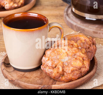 Beignets aux pommes glacés et tasse de café sur une plaque de bois Banque D'Images