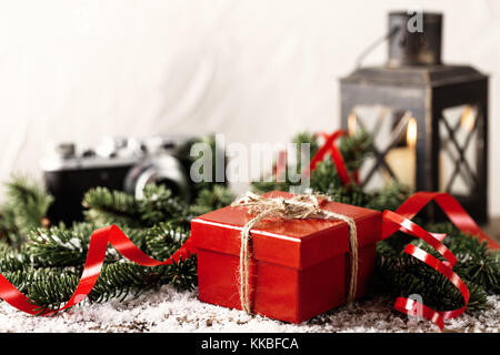 Boîte cadeau présent rouge avec caméra et porte-bougie de Noël sur fond de bois composition du nouvel an Banque D'Images