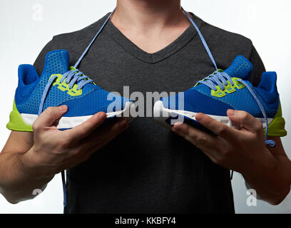 Man holding chaussures de course moderne concept isolé sur fond blanc. homme avec chaussures colorées sportive Banque D'Images