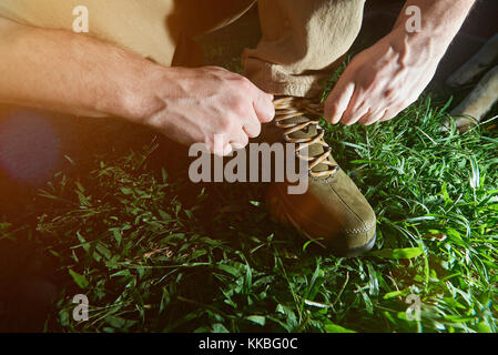 Des chaussures de randonnée de liage lace gros plan sur fond d'herbe verte.'attacher ses bottes Banque D'Images