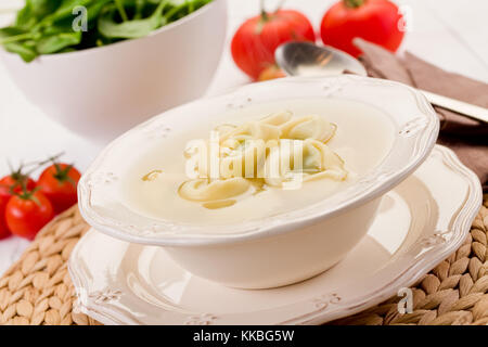 Pâtes tortellini délicieux dans un bouillon avec des légumes sur tableau blanc Banque D'Images