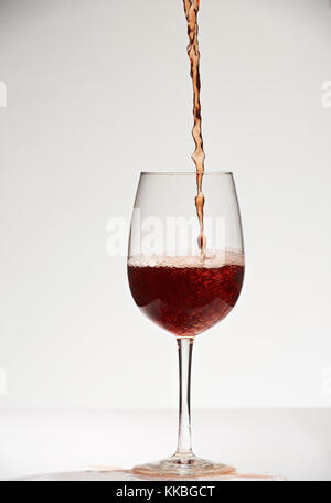 Verser le vin rouge dans le verre isolé sur fond blanc Banque D'Images