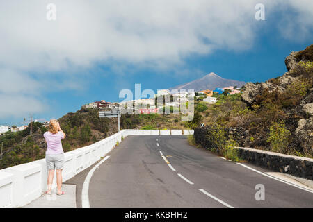 Le touriste féminin regarde à travers des jumelles vers le volcan Teide depuis le point de vue de la route de Mirador El Lagorito, El Tanque, Tenerife, les îles Canaries Banque D'Images