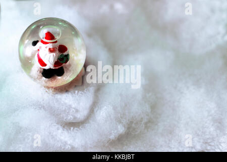 Crystal snow ball avec le père Noël à l'intérieur de la neige blanche fond flou avec l'espace pour le texte. Noël ou Nouvel An, modèle de carte de vœux. Banque D'Images