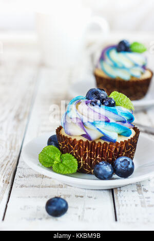 Cupcakes vanille délicate avec de la crème et les baies sur un fond de bois blanc Banque D'Images