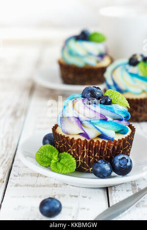 Cupcakes vanille délicate avec de la crème et les baies sur un fond de bois blanc Banque D'Images