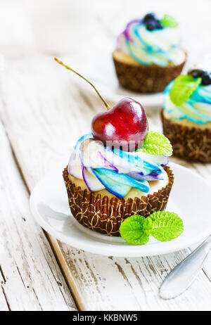 Cupcakes vanille délicate avec de la crème et les baies sur un fond de bois blanc Banque D'Images