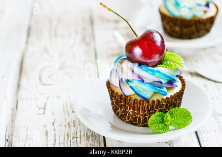 Cupcakes vanille délicate avec de la crème et les baies sur un fond de bois blanc Banque D'Images