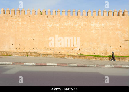 Femme marche par un ancien mur de la ville Banque D'Images