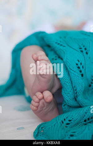 Bébé mignon petit talons pieds au-dessus de la couverture en tricot turquoise. verticale. Banque D'Images