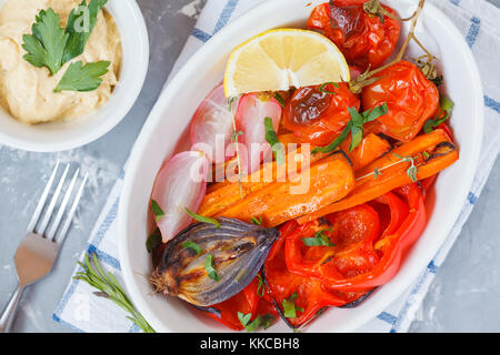 Les légumes cuits : carottes, radis, oignons, tomates et poivrons d'hummus dans une forme en céramique blanche saine alimentation detox vegan. concept. Banque D'Images