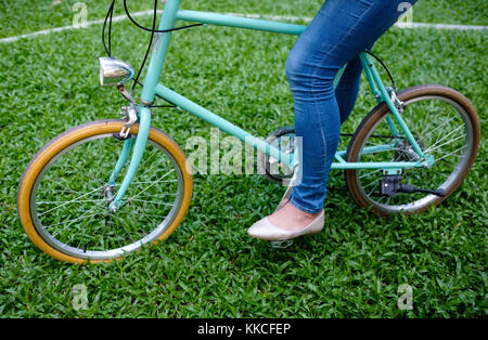 Location de style vintage bleu debout sur l'herbe verte avec femme en jeans. Banque D'Images