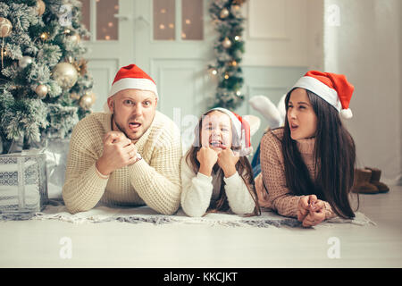 Noël en famille santa hats lying on bed. mère père et bébé s'amuser Banque D'Images