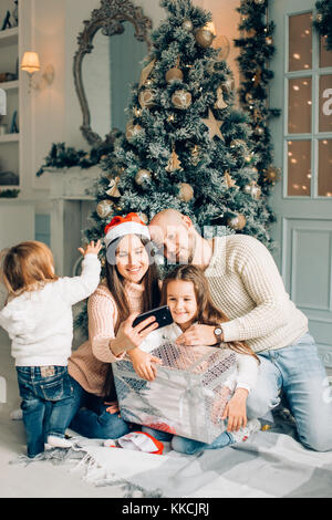 Famille de quatre jeunes heureux de prendre une photo d'eux-mêmes par une cheminée Banque D'Images