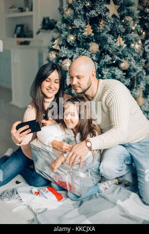 Famille de quatre jeunes heureux de prendre une photo d'eux-mêmes par une cheminée Banque D'Images