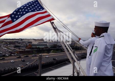 L'aviateur Jackie l Chess, à droite, salue l'aviateur de l'aviation Boatswain, Jose A Dominguez Rodriquez lève le drapeau américain lors d'une commémoration du Memorial Day sur le pont d'envol du porte-avions USS George HW, Norfolk. Image reproduite avec l'aimable autorisation de spécialiste en communication de masse 3rd Class Derrik Noack/US Navy, 2012. Banque D'Images