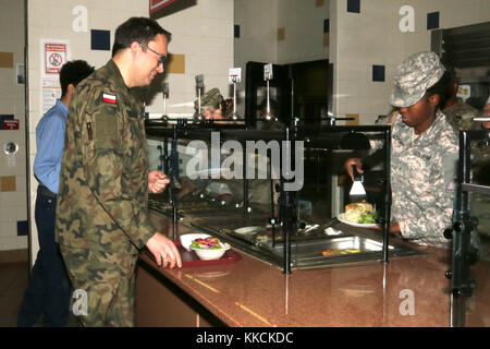 Le colonel Michal Sprengel, Attaché militaire polonais, commande de la nourriture de la ligne principale au café du soldat en fer de l’équipe de combat de la 3e Brigade blindée lors d’une visite à fort Bliss, Texas, le 17 novembre 2017. PFC. Ashely Williams, spécialiste culinaire, 1er Bataillon, 77th Armored Regiment, lui sert le saumon, la purée de pommes de terre et le brocoli. (É.-U. Photo de l'armée par le sergent d'état-major. Felicia Jagdatt) Banque D'Images
