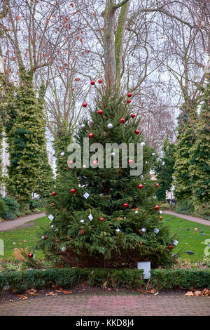 Close up d'un arbre de Noël décoré avec des boules rouge et argent dans un petit jardin Banque D'Images