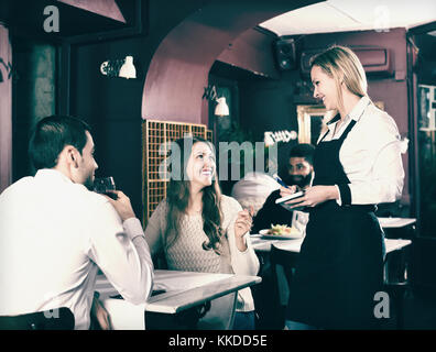 Adultes ayant des conjoints souriant ce jour en classe moyenne restaurant. se concentrer sur fille blonde Banque D'Images