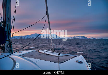 Sunrise over fjord avec montagnes couvertes de neige et paysage d'hiver vu de sailship près de Tromso, Troms, Norvège, Europe Banque D'Images