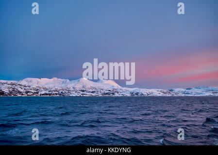 Sunrise over fjord avec montagnes couvertes de neige et paysage d'hiver vu de sailship près de Tromso, Troms, Norvège, Europe Banque D'Images