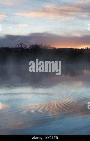 Lever du soleil et de l'eau réflexions ondulation sur un lac dans le village de Bourton on the Water. Cotswolds, Gloucestershire, Angleterre Banque D'Images