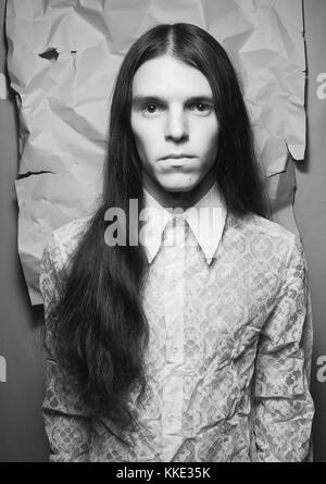 Portrait à l'ancienne d'un garçon brun sur fond de papier blanc froissé. noir et blanc, studio shot Banque D'Images