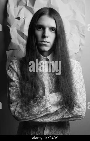 Portrait à l'ancienne d'un garçon brun sur fond de papier blanc froissé. noir et blanc, studio shot Banque D'Images