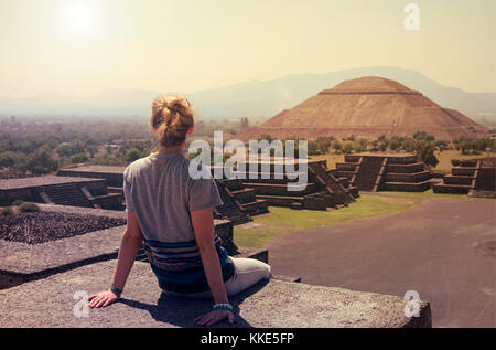 Jeune femme assise sur le haut de pyramide surplombant Teotihuacan lors d'une journée ensoleillée Banque D'Images